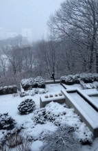 A fresh fall of snow blankets the reflecting pool, evergreen plantings and wooded hillsides – modernist structure prevails.