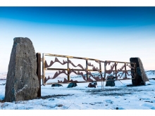 Upstanding stone pillars and a weathering steel gate mark the cemetery entrance