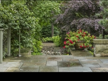 Salvaged paving with brushed stainless steel link traditional and modern. The peace pole acts as visual terminus with one of the owner's collection of pots creating a bright seasonal focal point.